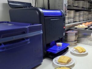 話題の“走る回転寿司”「SUSHI BUS」に、鈴茂器工のコンパクトシャリ玉ロボット「S-Cube」が導入！